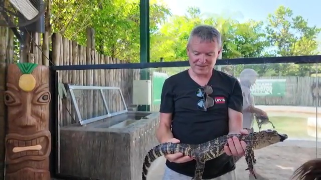 Man holding a small alligator.