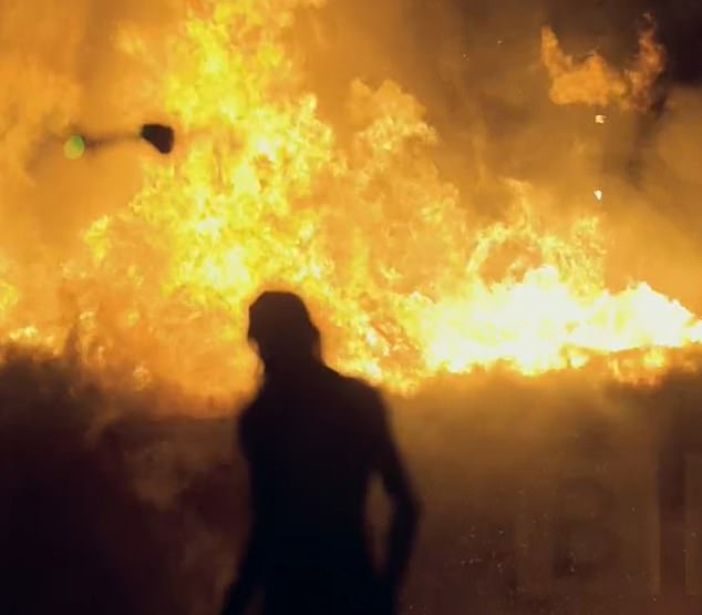 A naked Jhaj walks in front of the flames after the planned explosion