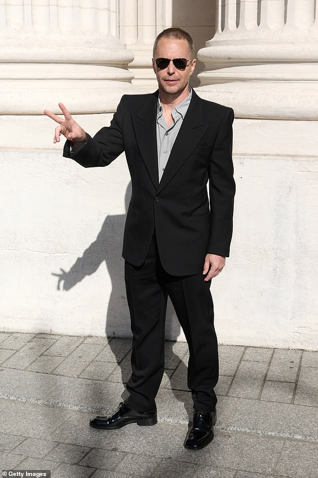 Sam kept it simple in a black suit and open grey shirt