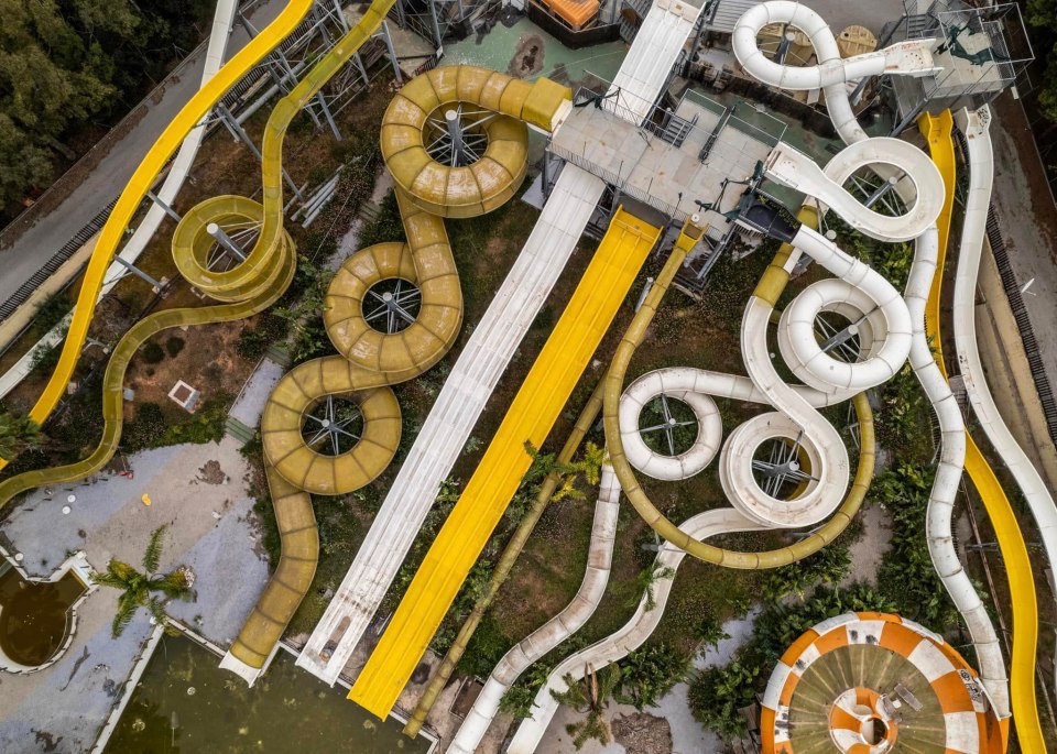 Aerial view of an abandoned water park with overgrown vegetation.