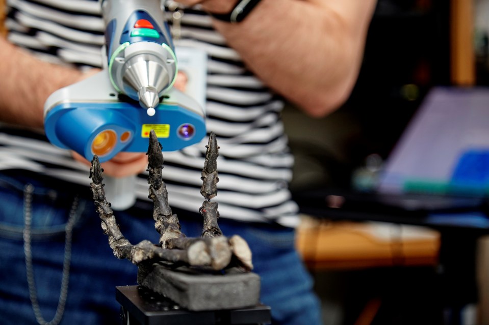 Person 3D scanning a dinosaur fossil hand.