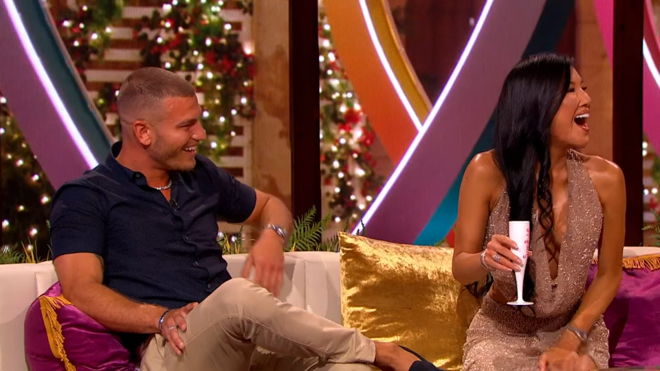 Man and woman laughing on a sofa.