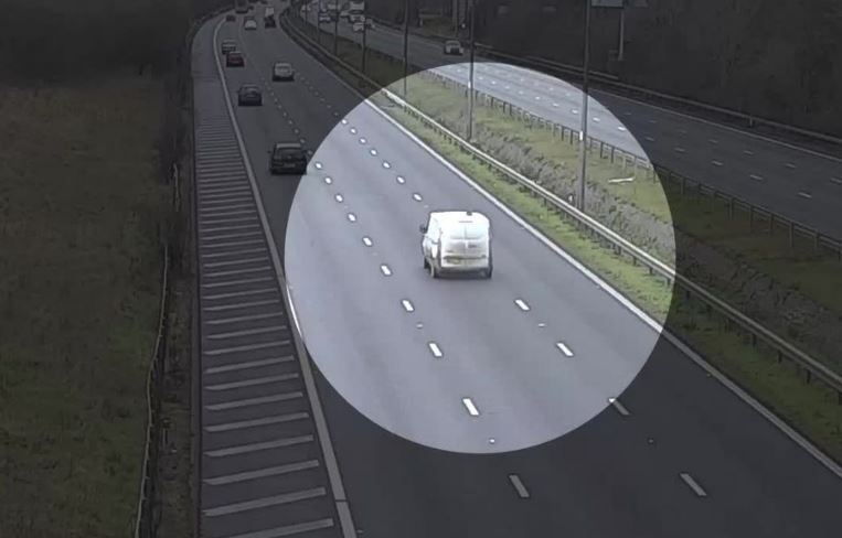 White van driving on a highway.