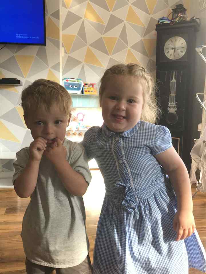 Two young children stand together.
