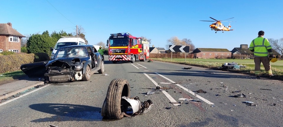 Aftermath of a car crash with a damaged Mini Cooper, a firetruck, and an air ambulance.