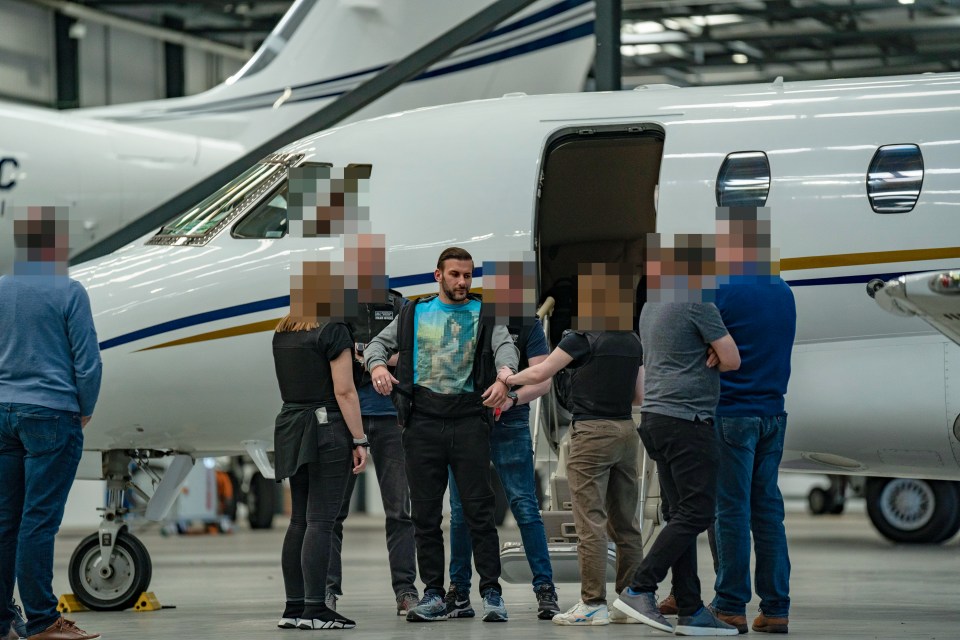 Blurred photo of James Harding's arrest by Metropolitan Police officers following extradition from Switzerland.