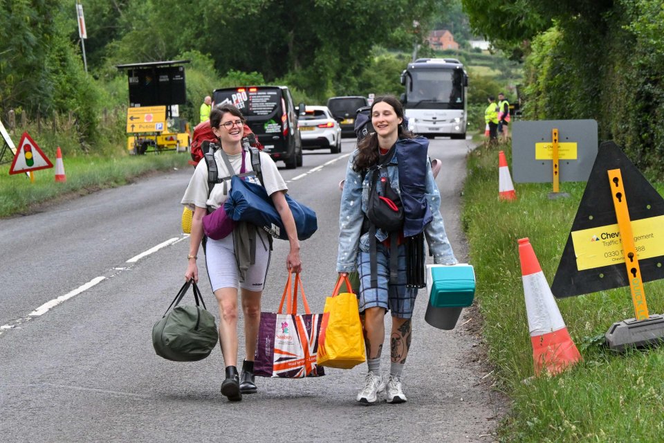 Two women walking to Glastonbury Festival carrying bags and backpacks.