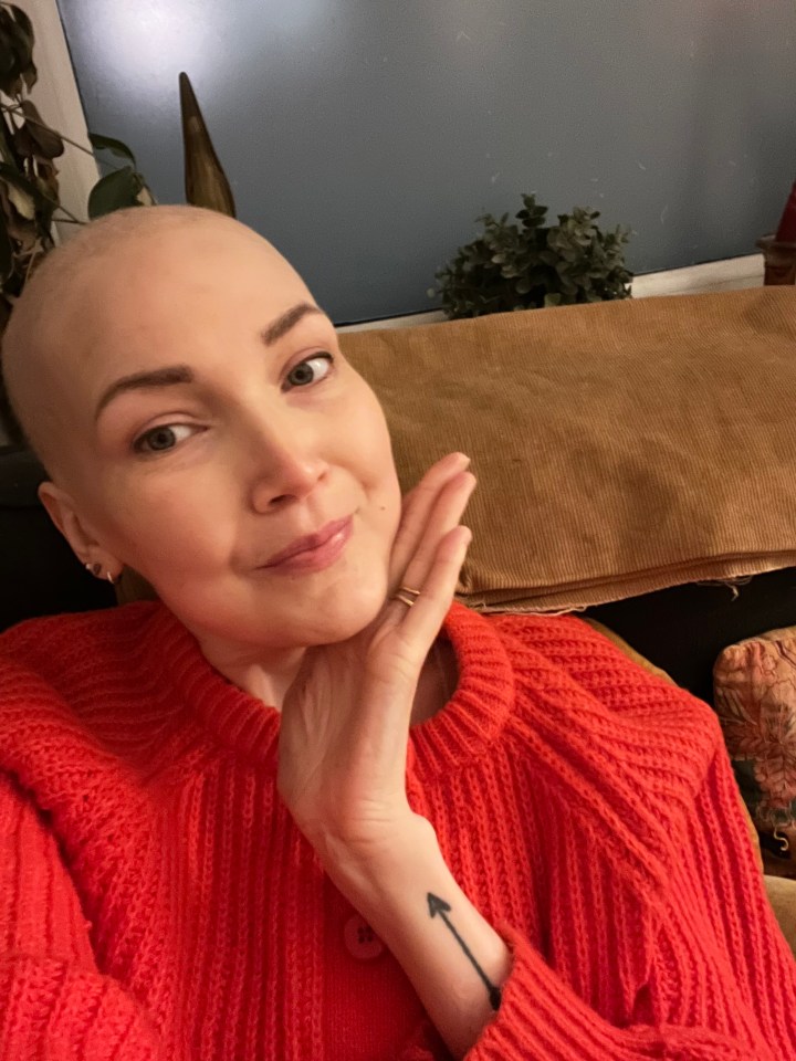 Woman with shaved head and red sweater.