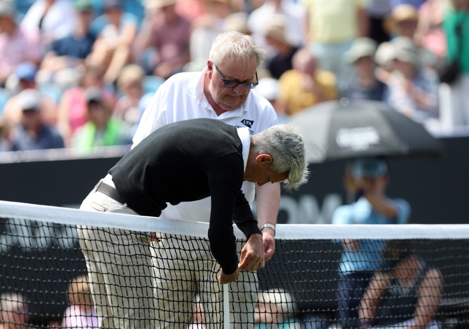 Umpire and groundstaff repairing a tennis net.