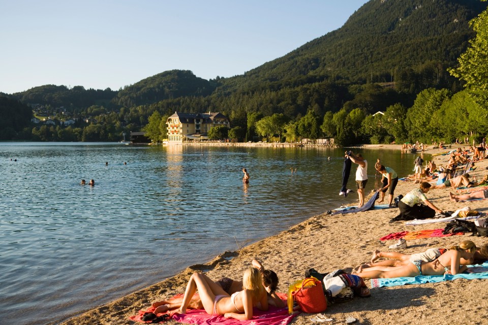 People relaxing on a sandy beach by a lake.