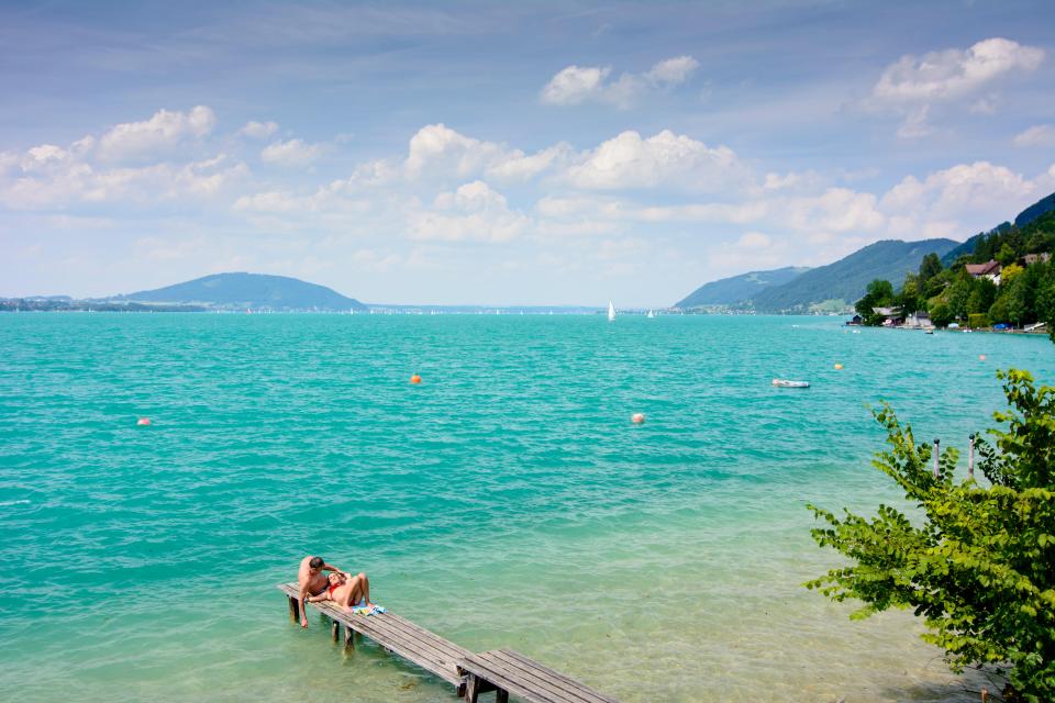 Couple relaxing on a jetty at Lake Attersee in Austria.