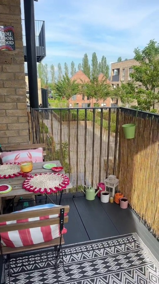 Balcony decorated with plants and patterned rugs, privacy screen made from bamboo.