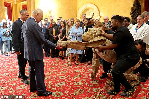 He's shaken hands with thousands of dignitaries over the years - but possibly never with a life-sized cardboard gorilla puppet. Still, the King took it all in his stride as he watched as he watched a performance of life-sized figurines at a climate finance reception