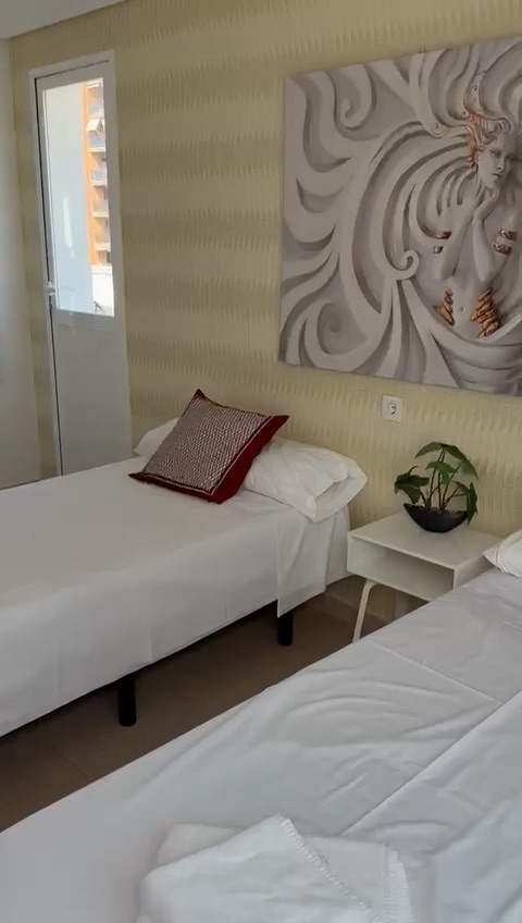 Bedroom with two twin beds, a white nightstand, and wall art.