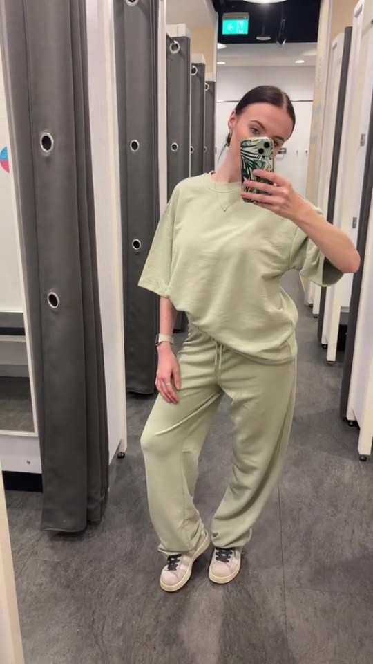 Woman in a sage green tracksuit in a Primark changing room.