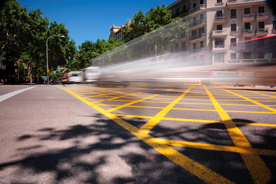 Motion blurred photo of cars driving through a city intersection.