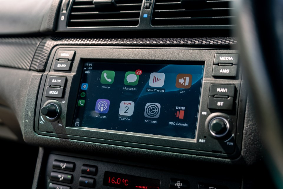 Car dashboard with screen displaying phone, messages, music, calendar, and other apps.
