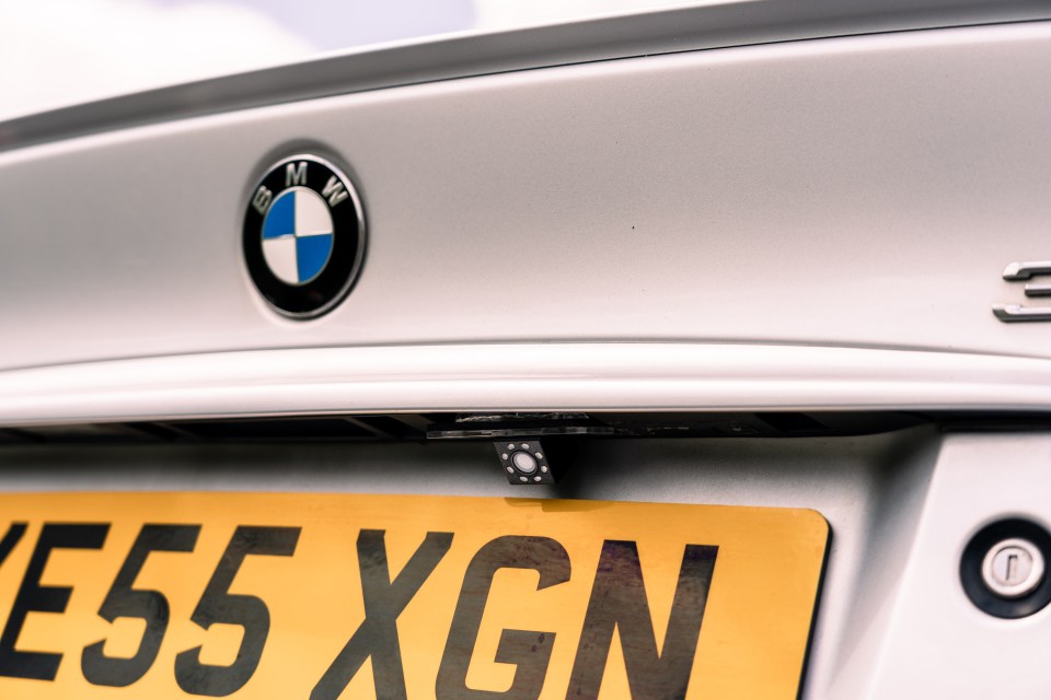 Close-up of a silver BMW's rear license plate and reversing camera.