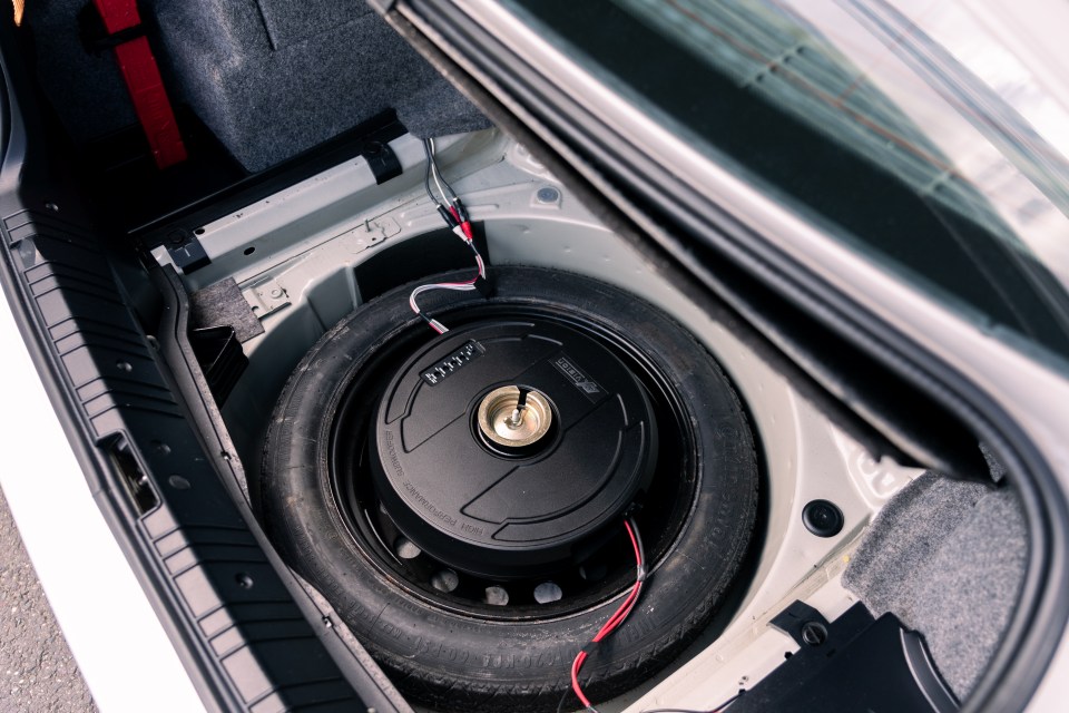 Car trunk with spare tire and subwoofer.