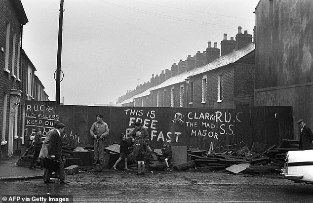Pictured: Children talk with British soldiers at a roadblock on a street in Belfast on September 21, 1969