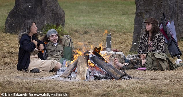 Revellers gather around a bonfire at the Stone Circle at Glastonbury Festival early this morning