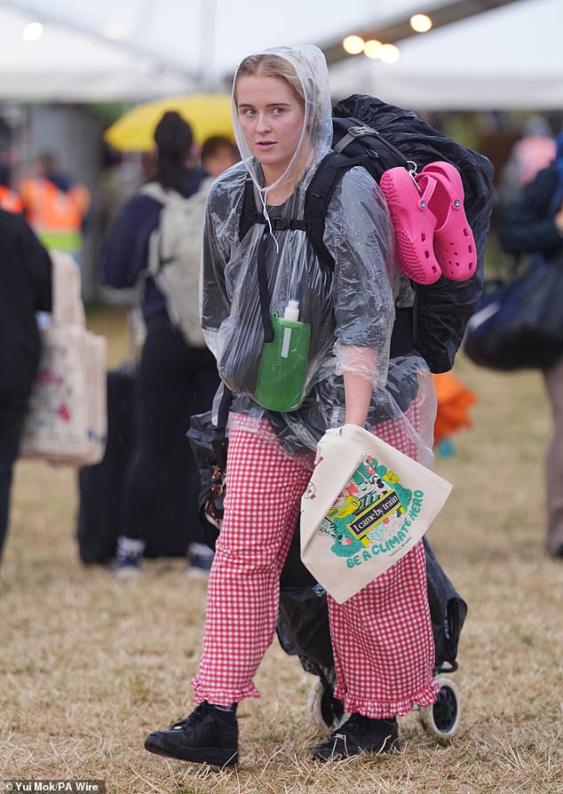 Revellers arrive at the Glastonbury Festival during a rain shower at Worthy Farm this morning