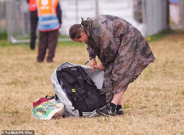 Revellers arrive at the Glastonbury Festival during a rain shower at Worthy Farm this morning