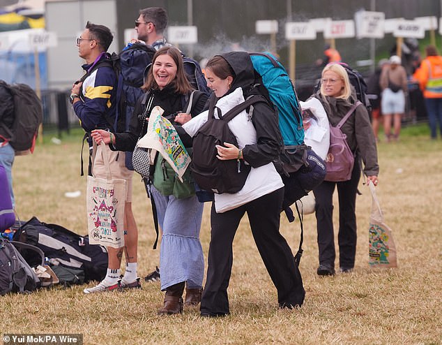 Revellers arrive at the Glastonbury Festival during a rain shower at Worthy Farm this morning