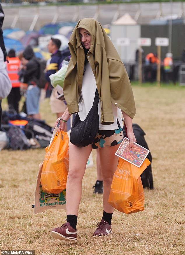 Revellers arrive at the Glastonbury Festival during a rain shower at Worthy Farm this morning