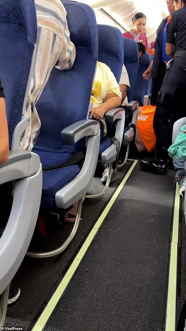 Police and airline staff are seen dragging the man onto the floor