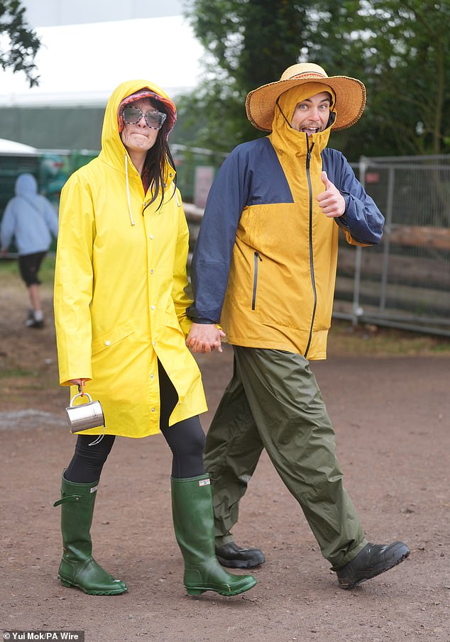 Revellers at the Glastonbury Festival during a rain shower at Worthy Farm in Somerset today