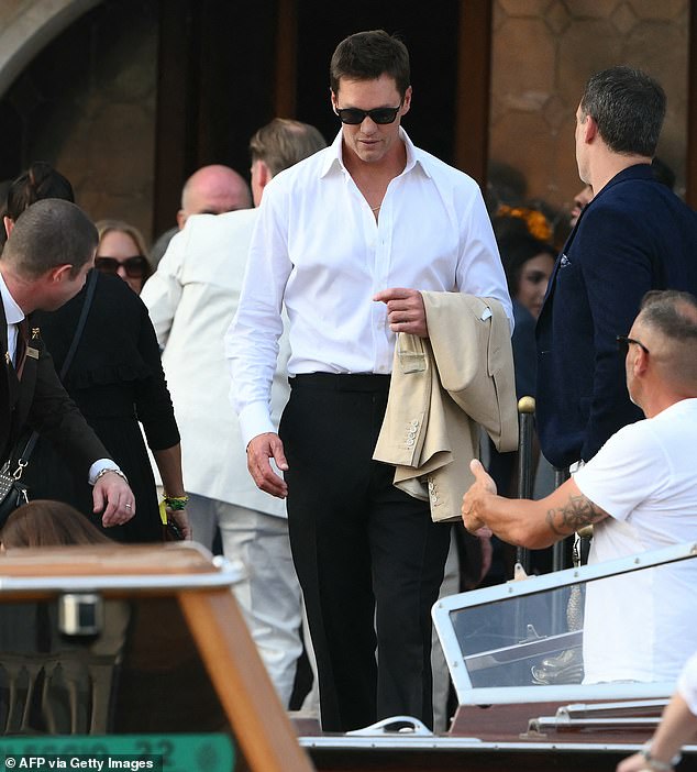 Football star Tom Brady was spotted in a button-down white shirt and black dress pants; he held a tan sports jacket to complete the look