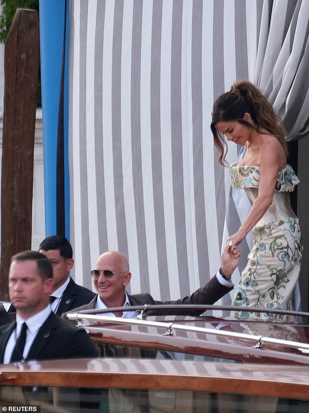 Having kept a low profile for the last two days (wearing a black Alaia dress on her arrival followed by vintage Alexander McQueen on Wednesday night), Lauren Sanchez today stunned in a satin, off-the-shoulder Schiaparelli gown embroidered with flowers and birds. She is seen leaving the five-star Aman Venice hotel with her husband-to-be Jeff Bezos