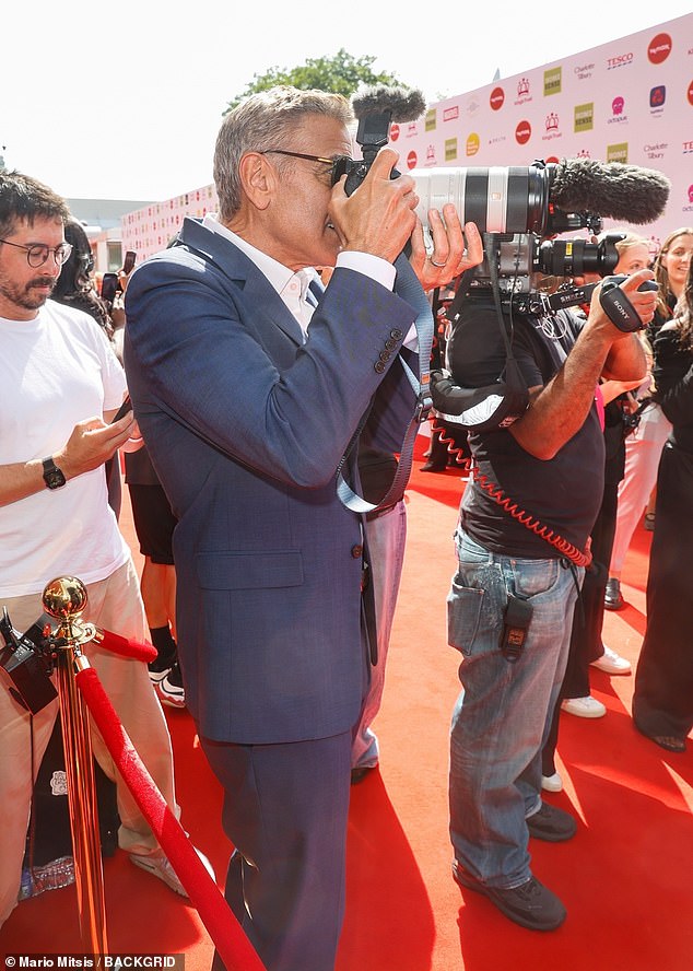 George was seen borrowing a photographers camera as he snapped pictures of his stunning wife
