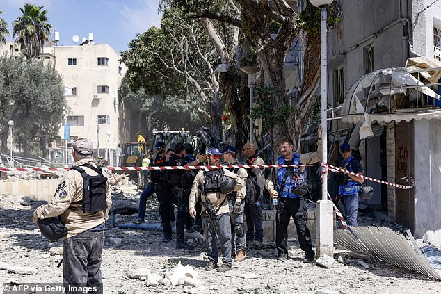 Israeli first responders and troops work in front of a building hit during an Iranian strike in the port city of Haifa on June 22, 2025