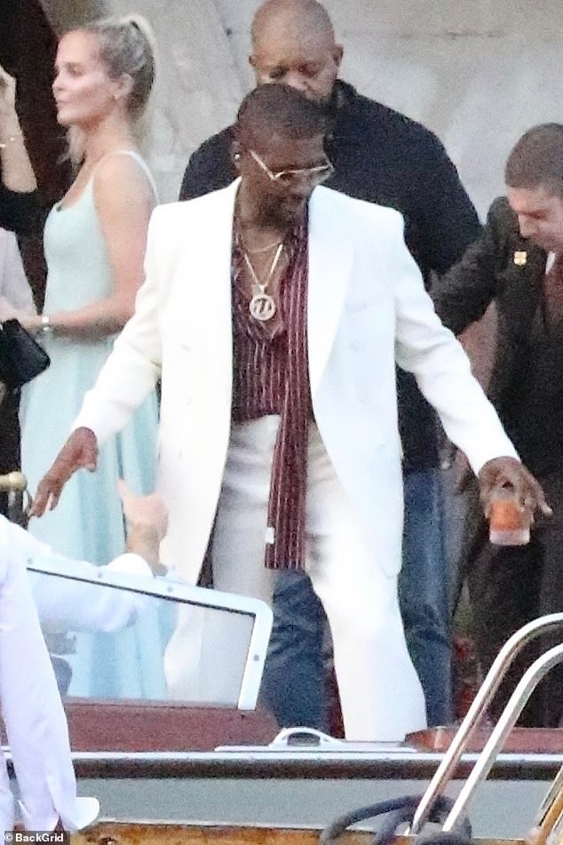 Usher, 46, looked stylish in a white suit over an avant-garde red striped shirt