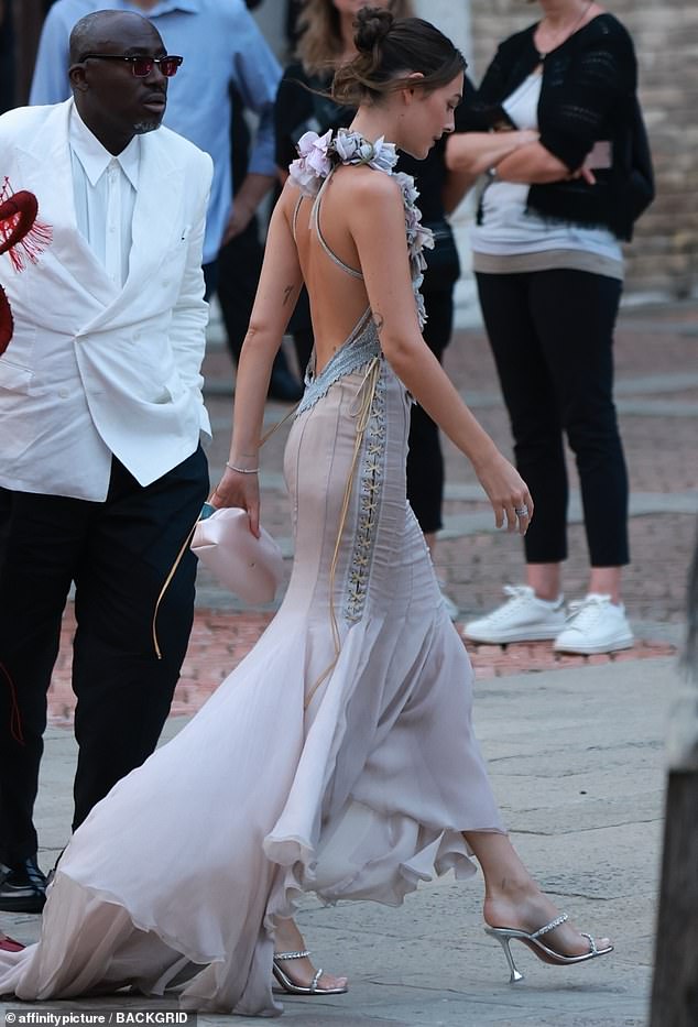 She added a touch of sparkle to the look with a glittering necklace and matching bracelet, carrying a rose pink clutch designed to resemble a flower
