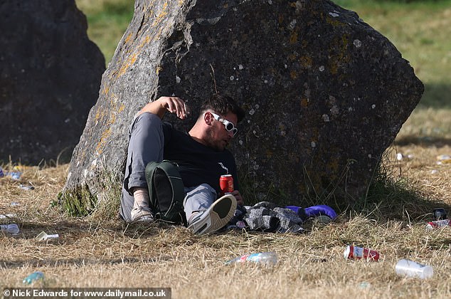 A Glastonbury festivalgoer rests in the sunshine at Worthy Farm in Somerset this morning