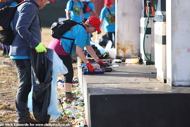 Litter pickers collect nitrous oxide canisters during the Glastonbury morning clean-up today