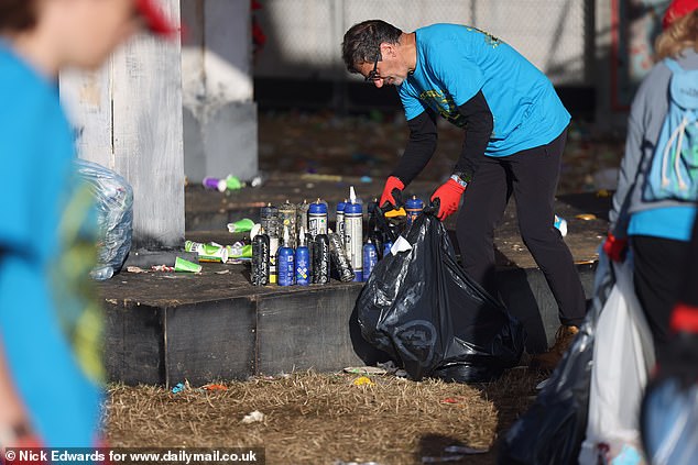 Litter pickers collect nitrous oxide canisters during the Glastonbury morning clean-up today