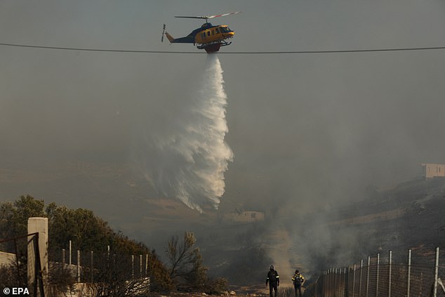 GREECE: A firefighting helicopter douses a wildfire burning in the coastal region of Palaia Fokaia
