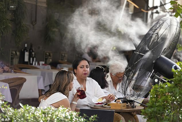 SPAIN: People sit next to a large outdoor fan to keep cool at a restaurant terrace during high temperatures in Madrid