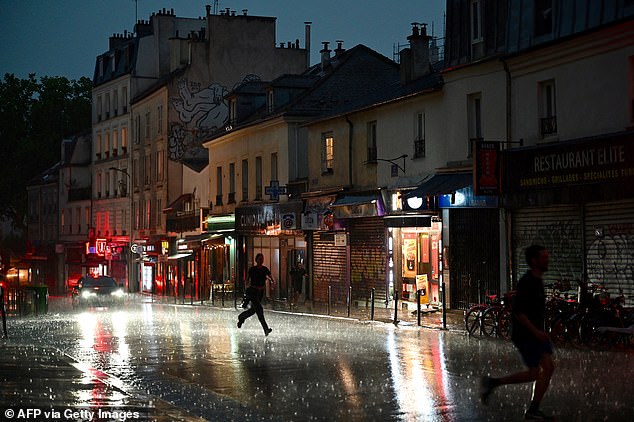 FRANCE: People run for shelter on a street in the 20th Arrondissement during a thunderstorm, in Paris, on June 25