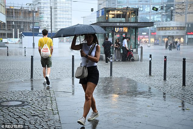 GERMANY: A woman shields herself with an umbrella on Alexanderplatz square