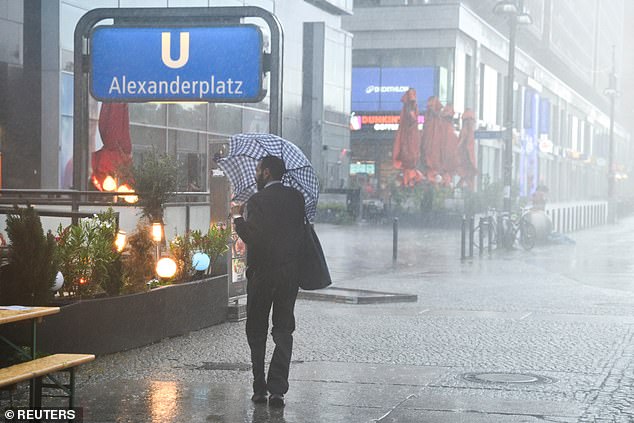 GERMANY: A man shields himself with an umbrella on Alexanderplatz square during stormy weather in Berlin