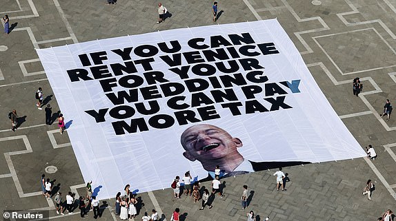 A large banner against Amazon founder Jeff Bezos lies on the ground, placed by Greenpeace Italy activists along with others in St. Mark's Square, ahead of the expected wedding of Amazon founder Jeff Bezos and Lauren Sanchez, in Venice, Italy, June 23, 2025. REUTERS/Yara Nardi