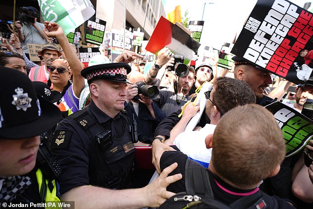 Police officers remove a counter-protester from the middle of supporters of Kneecap