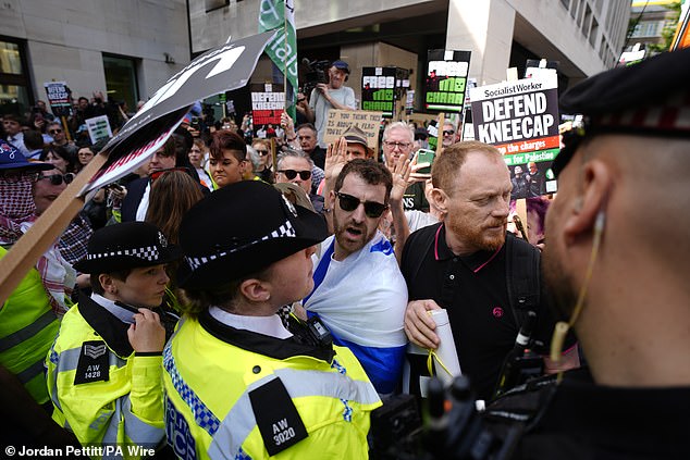 Police officers remove a counter-protester from the middle of supporters of Kneecap on June 18