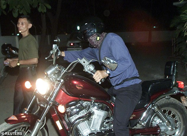 Gary Glitter, with his face covered with a scarf, leaves the Phnom Penh police department in Cambodia after collecting his passport