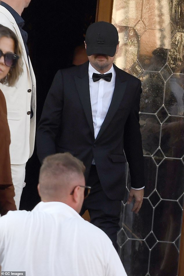 Orlando had been out partying poolside with Leonardo Di Caprio, 50, who kept a low profile in a cap (Pictured later in the day on his way to the wedding)